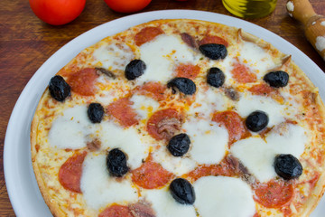 pizza with black olives and pepperoni on a wooden table