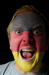 Face of crazy angry man painted in colors of germany flag