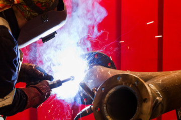 factory worker welding metal and sparks spreading
