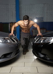 Fashion portrait of  young muscular man standing between cars