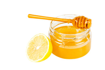Jar of honey with a wooden drizzler and a lemon.