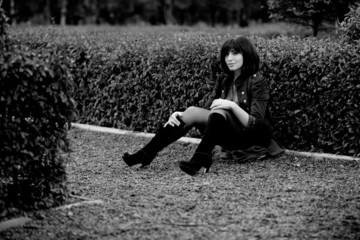 Fototapeta premium Young caucasian girl sitting on ground near bush