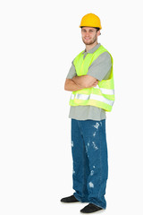 Side view of smiling young construction worker with arms folded
