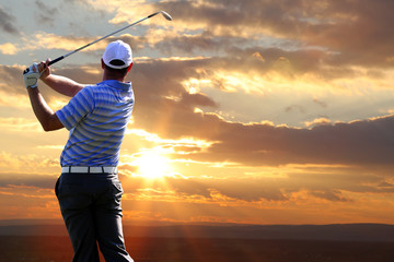 Homme jouant au golf contre le coucher du soleil