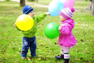 Двое малышей играют воздушными шариками