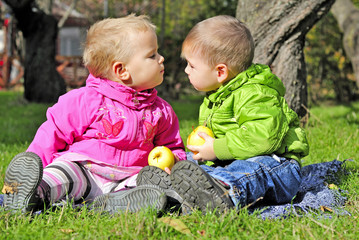 Двое малышей целуются на зеленой полянке