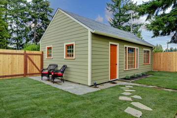 Fototapeta na wymiar Small green and orange guest house in the back yard