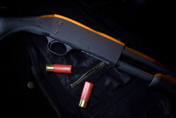 shotgun and shotshell ammo on a dark surface and red rim lighting coming from above.