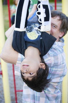 Active disabled five year old boy playing on the  monkey bars wi