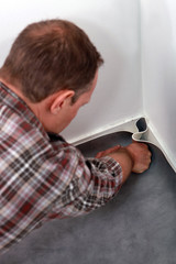 Man pushing linoleum into the corner of a room
