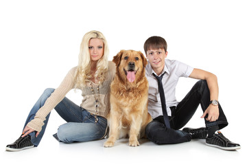 A young family with a dog sitting on floor, looking at camera