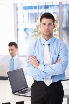 Confident businessman standing in bright office
