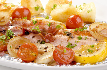 Forellenfilet auf einem Teller mit gegrilltem Speck und Gemüse