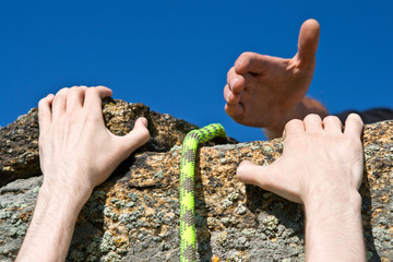 Rock climber reaching for helping-hand partner.