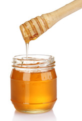 Jar of honey and wooden drizzler isolated on white