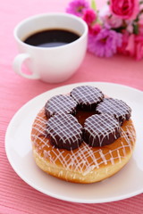 sweet chocolate donut with a cup of coffee and flower