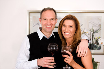 Paar lächelnd mit einem Glas Rotwein in der Hand
