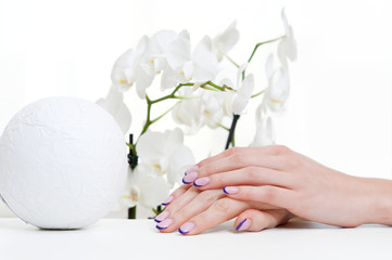 Hands with manicure, white orchid and decoration element