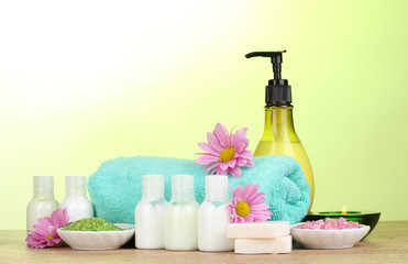 Hotel amenities kit on wooden table on green background
