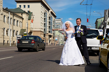 Funny bride and groom catch taxi on the street