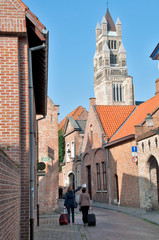 Tourist on old street and Notre Dame Belfry at Brugge - Belgium