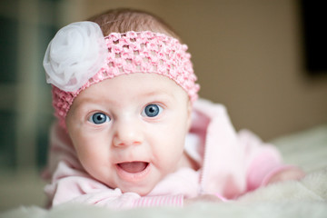 Baby in rosa mit Kulleraugen lacht