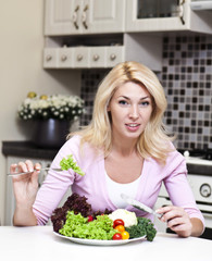 Pretty blonde woman eating some vegetables