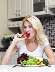 Pretty blonde woman eating some vegetables