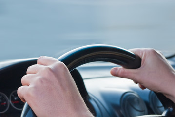 Driver's hands on a steering wheel of a car