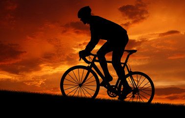 silhouette of the cyclist riding a road bike at sunset