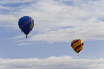 Two colorful hot balloons compete in the air.