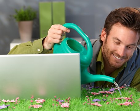 Cheerful man watering spring field table