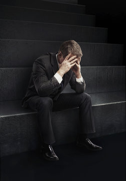 Young businessman sitting on stairs with head down