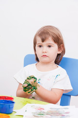 little girl draws paint sitting at the table