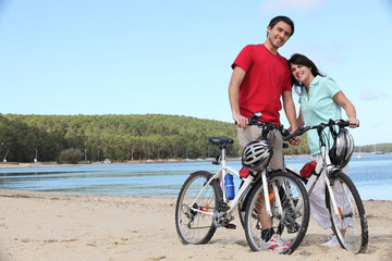 Fototapeta premium Young couple with bikes on a beach