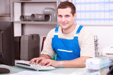 Young plumber in an office working on a computer