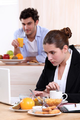 Career woman eating breakfast while working