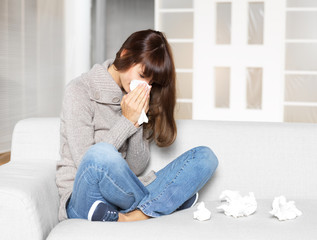 young woman is ill, blowing her nose