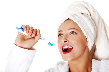 Smiling teen girl putting toothbrush to her mouth.