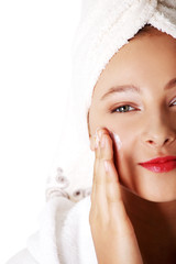 Teen girl in robe putting creme on her face.