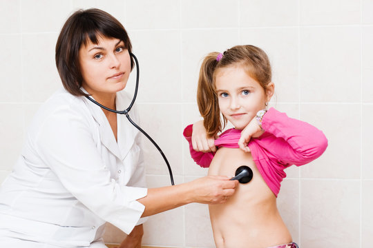 Female doctor examining child with stethoscope at clinic