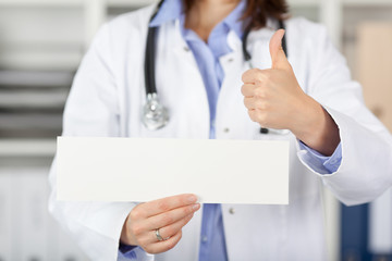 ärztin mit schild zeigt daumen hoch