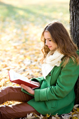 Obraz premium Young woman reading book in the park
