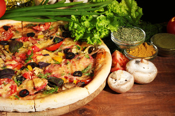 delicious pizza, vegetables and spices on wooden table