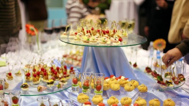 Hands take canapes from appetizer table with wine