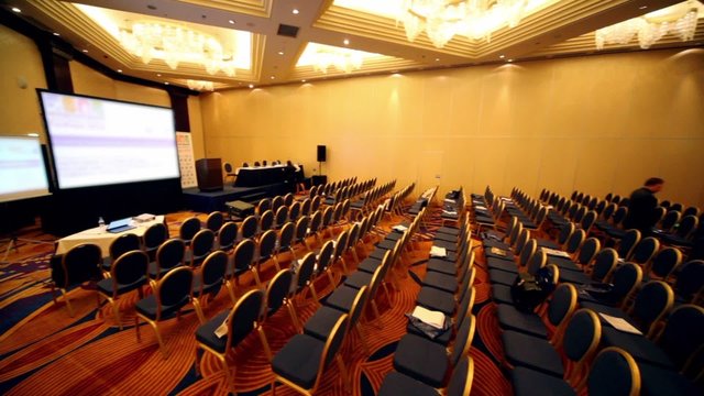 People walk in empty conference hall during break
