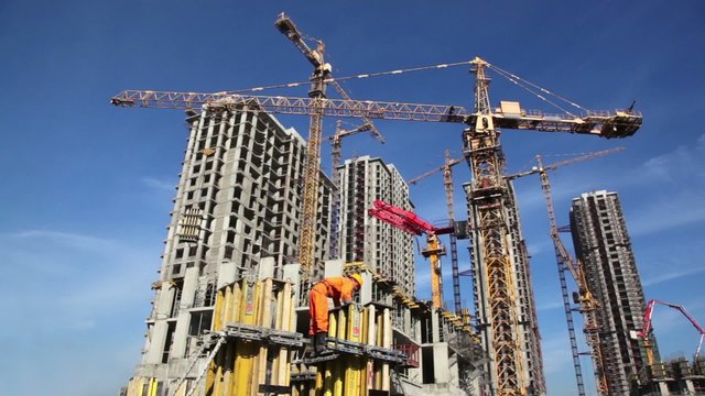 Builder works in front of many tall buildings under construction