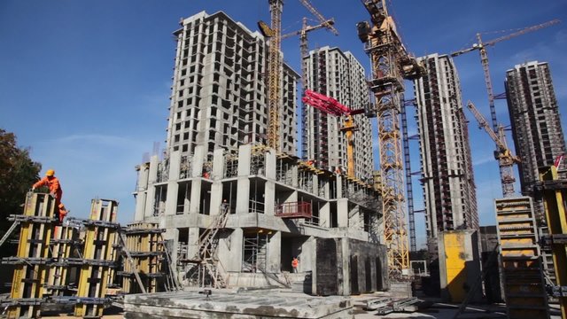 Workers lift valve using a high crane on construction site