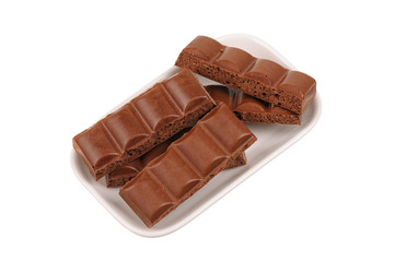 Cracked chocolate bar in a dish on white
