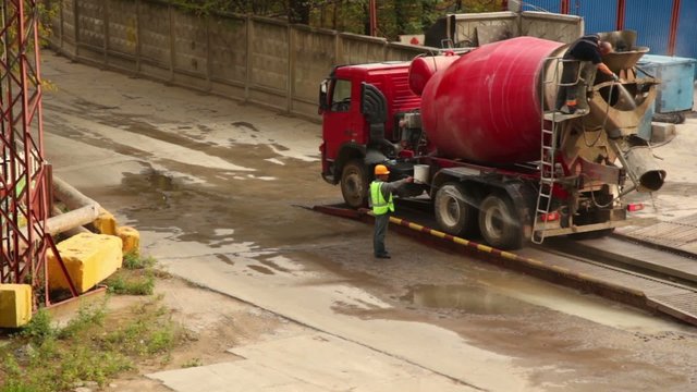 Two workers wash concrete mixer